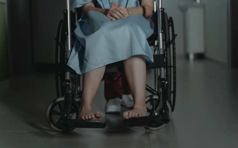 병원 복도에서 휠체어를 밀며 걷는 사람들