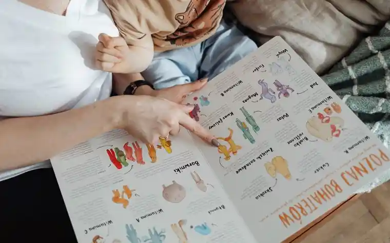 바닥에 앉아 그림책을 함께 보는 아이와 보호자