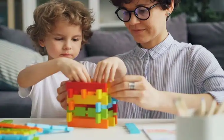 An adult and a child fitting coloured blocks together at a table