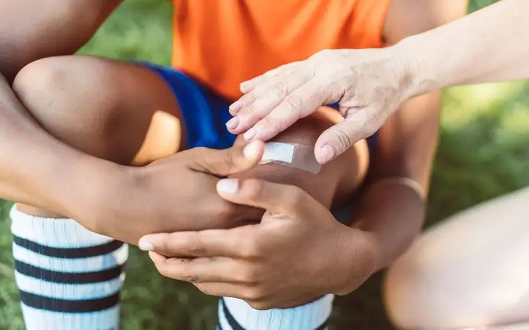 An adult's hands putting a plaster on a child's hand